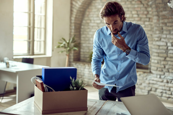 Shocked businessman reading a notice after being fired at work.